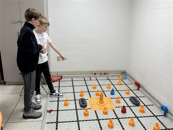 Students develop a strategy on the VEX IQ field.